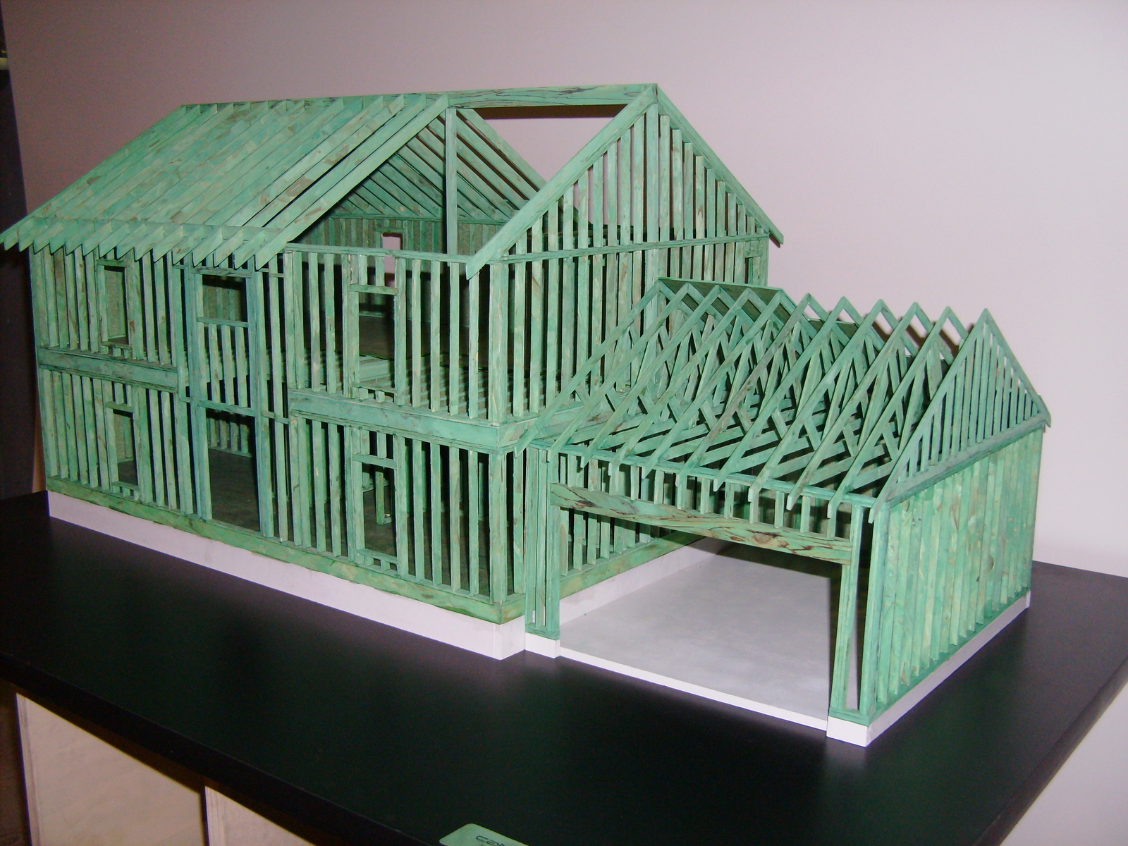 This model house I built in 1:12 scale for Weyerhouser to be displayed at trade shows. Its green coating illustrates an new product that year. It is made from actual Weyerhouser lumber product milled down and framed to code. The section of roof is missing to be able to see the interior.